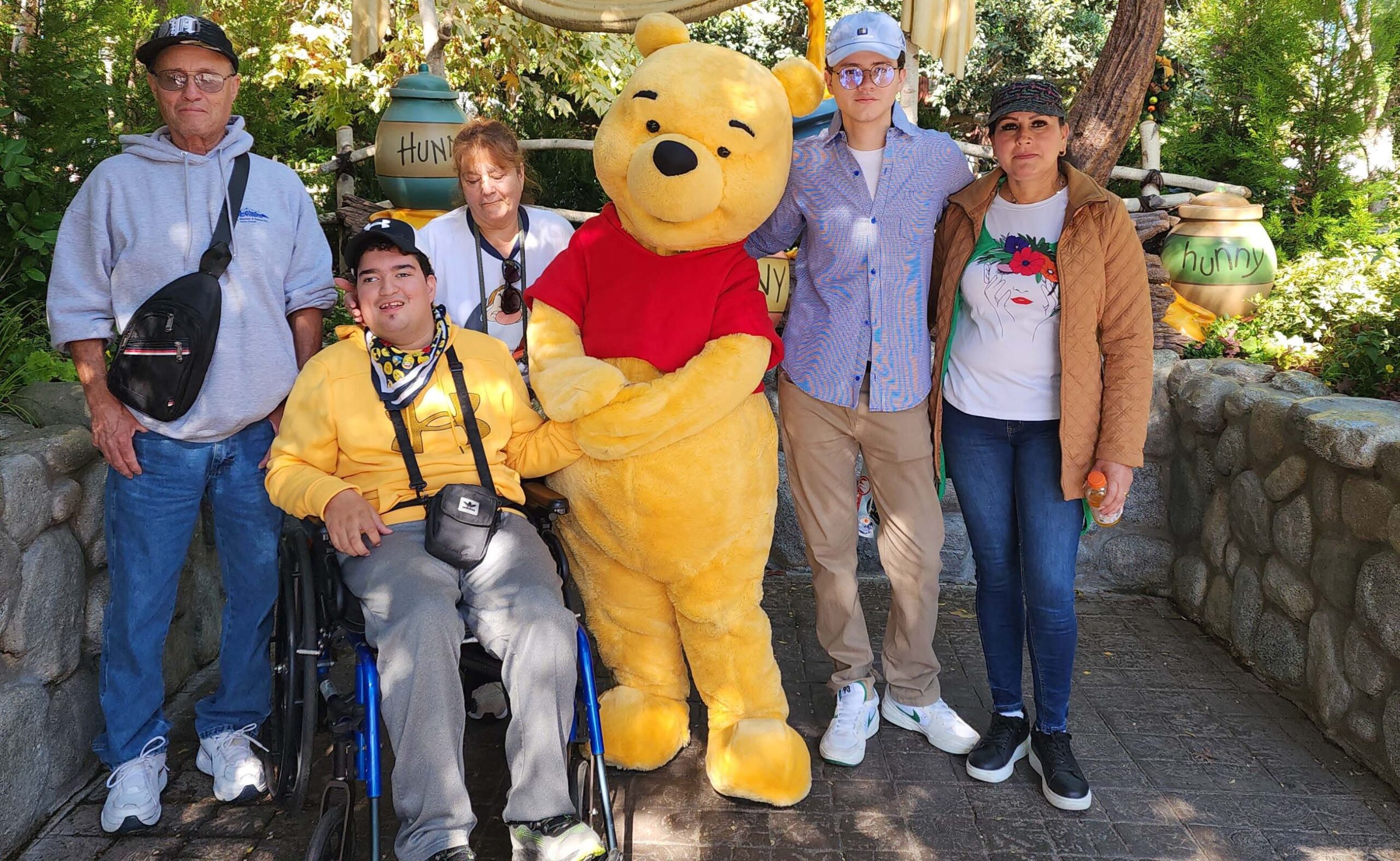 a group of people posing with winnie the pooh at disneyland