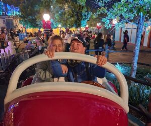 two people are riding in a car ride at disneyland at night