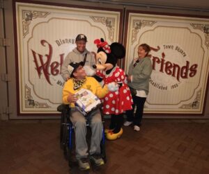 a person in a wheelchair is standing next to a minnie mouse