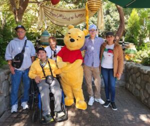 a group of people posing with winnie the pooh at disneyland