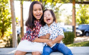 Two children sitting on a bench laughing